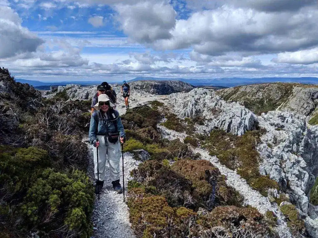 Group trekking rocky alpine trail on Cradle Mountain 4-Day Hike, highlighting Tasmania's rugged terrain and guided outdoor adventure experience.