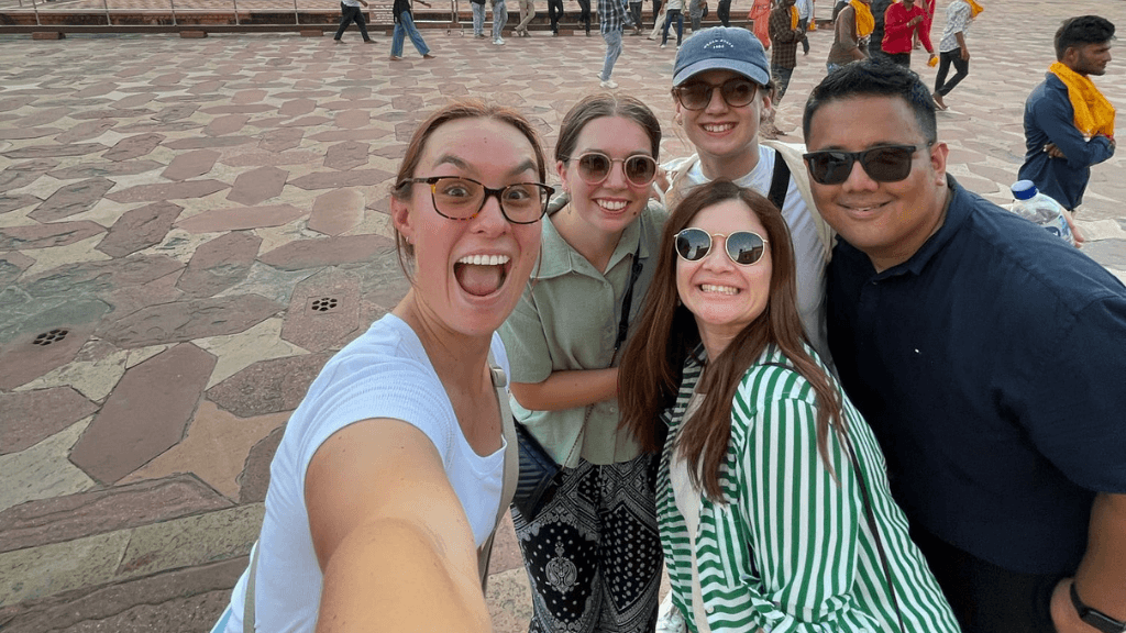Group selfie of travelers at a heritage site during 12 Day India Cultural Tour - Palaces & Sacred Cities. Fun group travel experience in India.