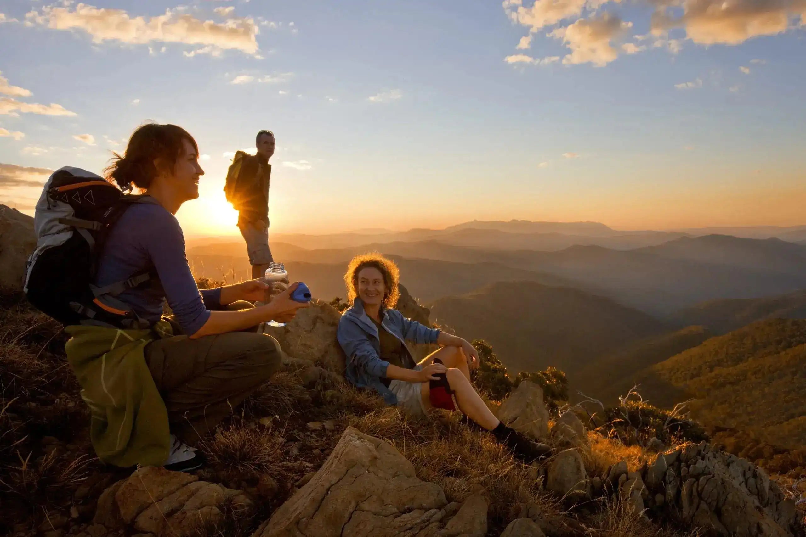 Group of hikers enjoying sunset views over mountain ranges during the Victorian Alps Walking Tour. Perfect for active explorers in Australia.