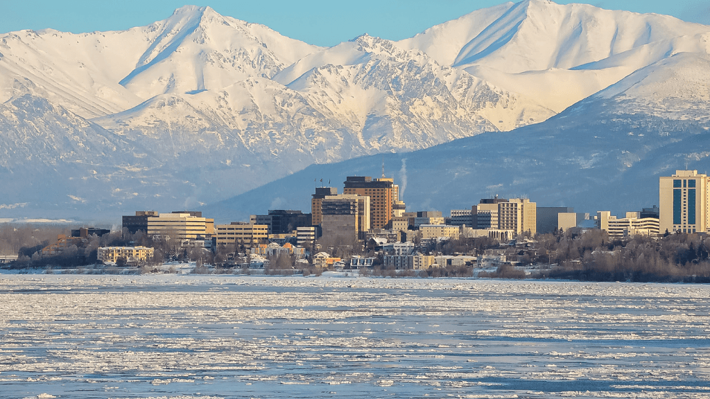 Anchorage skyline with snowy peaks in the background, a stop on the 8-Day Alaskan Adventure: Glaciers & Grizzlies tour.