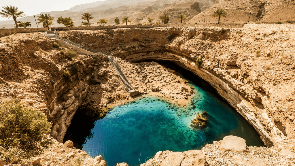 Bimmah Sinkhole with clear blue water surrounded by rocky cliffs, a natural wonder on the Oman 8 Day Adventure - Desert Stars & Turtle Shores tour.