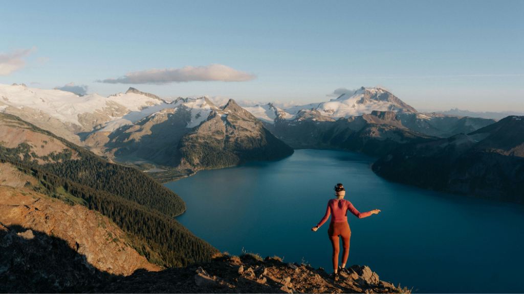 Traveler enjoying sunrise over alpine lake and rugged peaks on the Explore Rockies 8-Day Tour - Scenic Peaks | Hotel Stays. A serene moment in the Canadian Rockies.