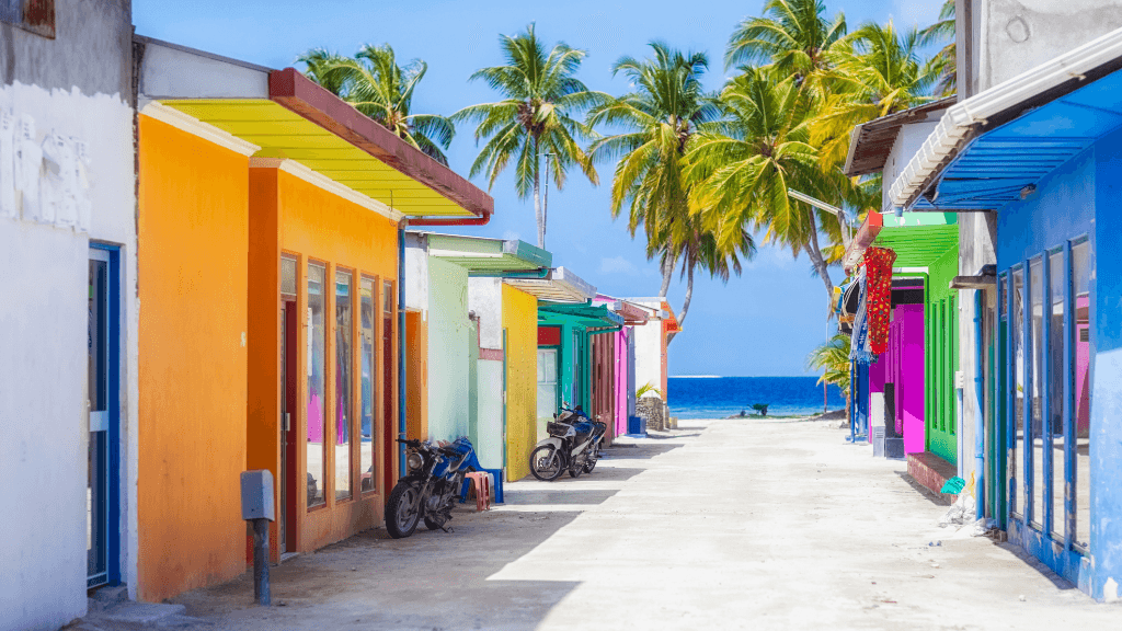 Colorful island village street with palm trees and ocean view, part of the Maldives Snorkel Adventure - 7-Day Escape.
