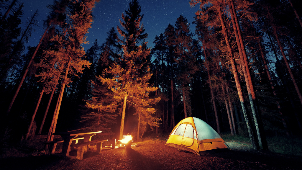 Night camping scene with lit tent and campfire in forest on the Vancouver Calgary Rockies Tour - 14 Days | Scenic Travel. Ideal for camping enthusiasts.