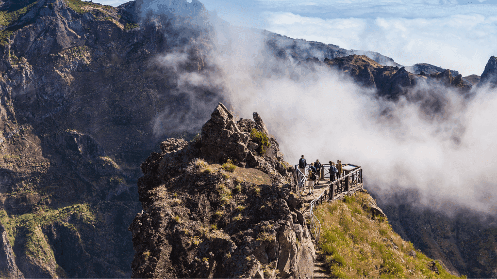 Hikers on a cliffside viewpoint above the clouds in Madeira, a highlight of the 6-days hiking Madeira’s trails journey.
