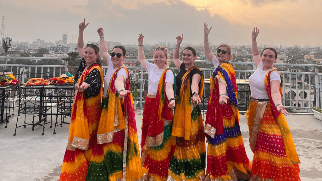Tourists in colorful sarees posing on a rooftop during 12 Day India Cultural Tour - Palaces & Sacred Cities. Cultural dress-up experience in India.