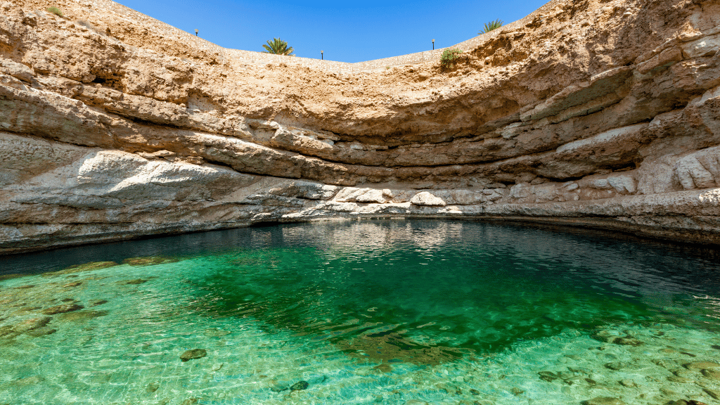 Bimmah Sinkhole with emerald water and rocky surroundings, a natural attraction on the Oman 8 Day Adventure - Desert Stars & Turtle Shores route.