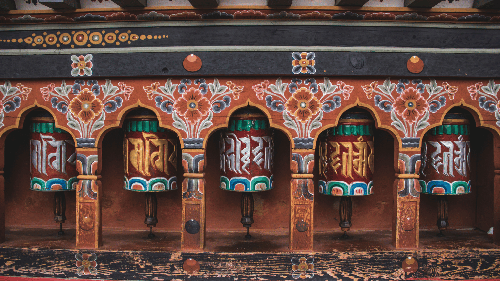 Colorful prayer wheels with intricate carvings, a spiritual element of the Trans Bhutan Trail cultural journey.