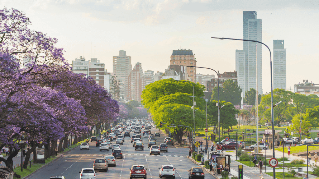 Busy avenue in Buenos Aires with jacaranda trees, included in the Quito to Rio South America tour from 15 to 65 days.