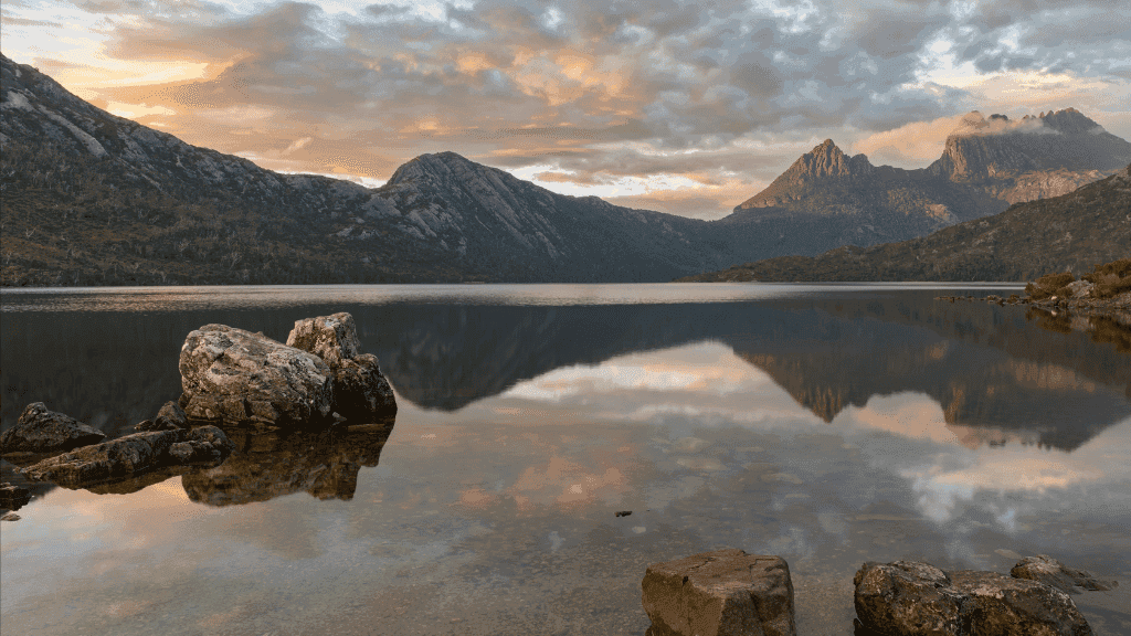 Sunset reflection over Dove Lake with Cradle Mountain peaks during 4-Day Hike in Tasmania, showcasing serene wilderness for nature lovers.