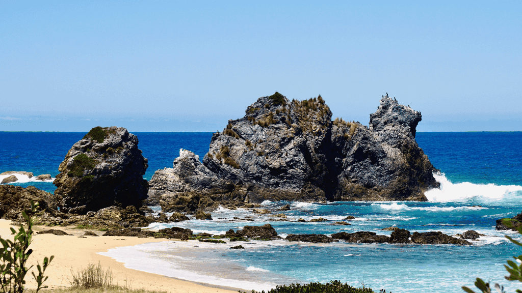 Dramatic sea stacks and turquoise waters along the Sapphire Coast Trek route, highlighting natural rock formations and coastal beauty.