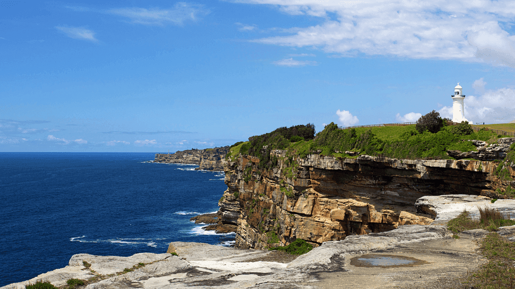 Dramatic cliffside with lighthouse overlooking the ocean, part of scenic landscapes explored on the Gordon River Kayaking adventure.