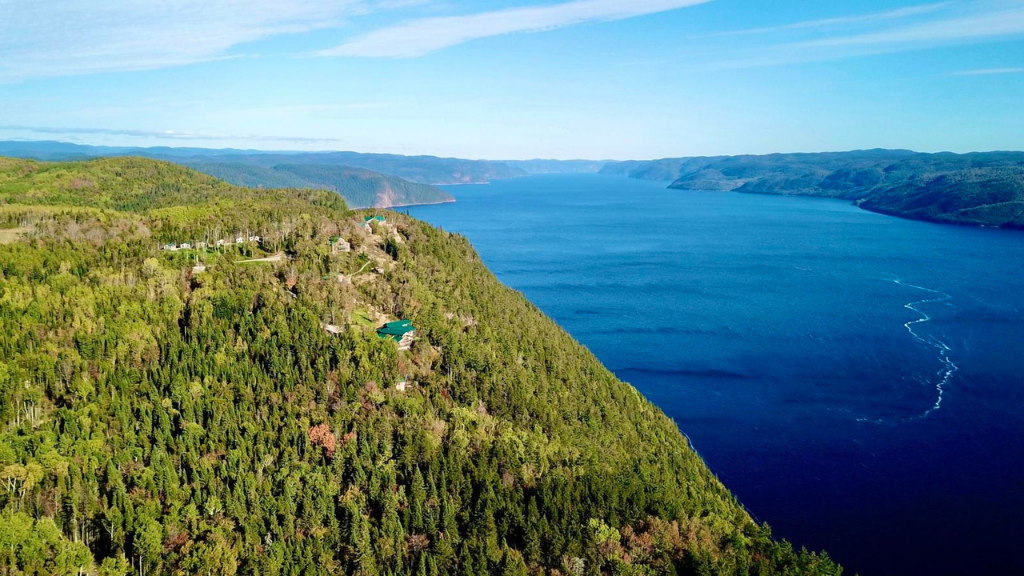 Aerial view of Saguenay Fjord and forested cliffs in Northern Québec. Highlight of the 7-day lodge escape with kayaking and hiking.