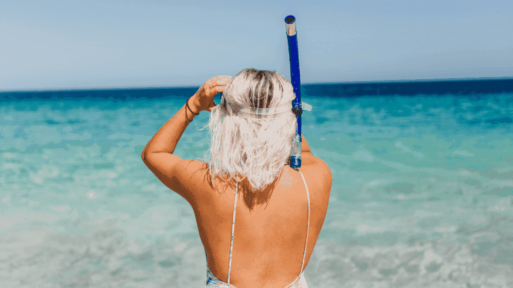 Woman with snorkel gear gazing at the ocean, ready to explore Ningaloo Reef during the 4-Day Kayak Expedition & Camp Adventure.