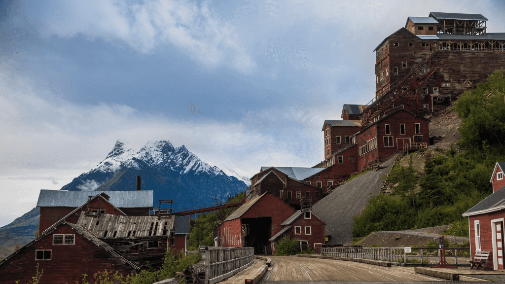 Historic red buildings of Kennecott Mine with mountain backdrop featured in the Ridge Walks & Ice Treks - 14-Day Alaskan Adventure tour.