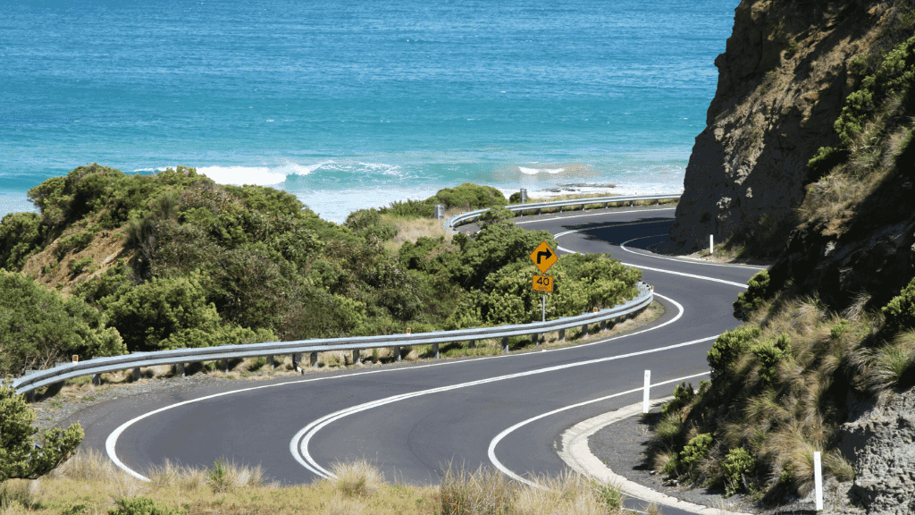 Winding coastal road along turquoise waters, ideal for adventurous outdoor travelers exploring the Great Ocean Walk.