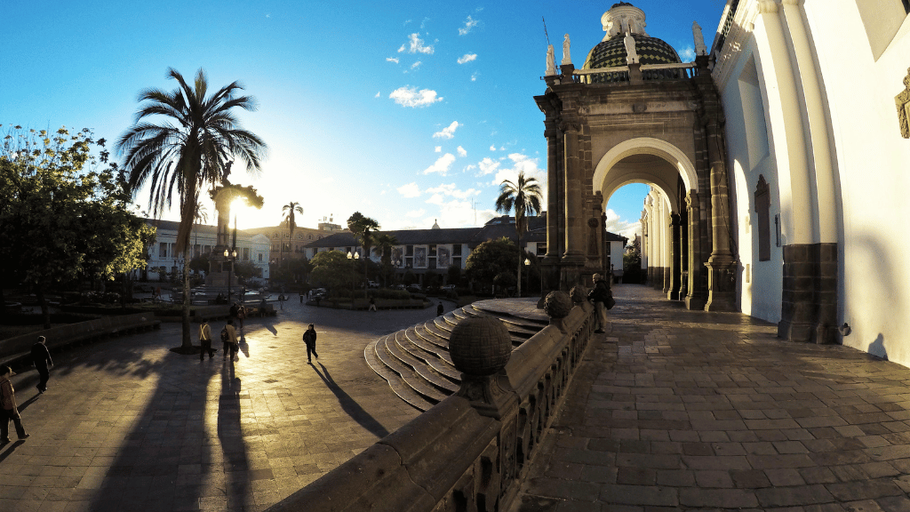 Colonial architecture and palm trees in Quito's historic center, featured in the Amazon Homestay Adventure - Canoes, Cacao & More | Quichua Living.