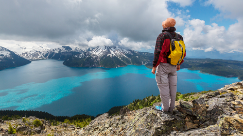 Hiker overlooking turquoise lake and snowy peaks on the Explore Rockies 8-Day Tour - Scenic Peaks | Hotel Stays. Ideal for gentle exploration and nature lovers.