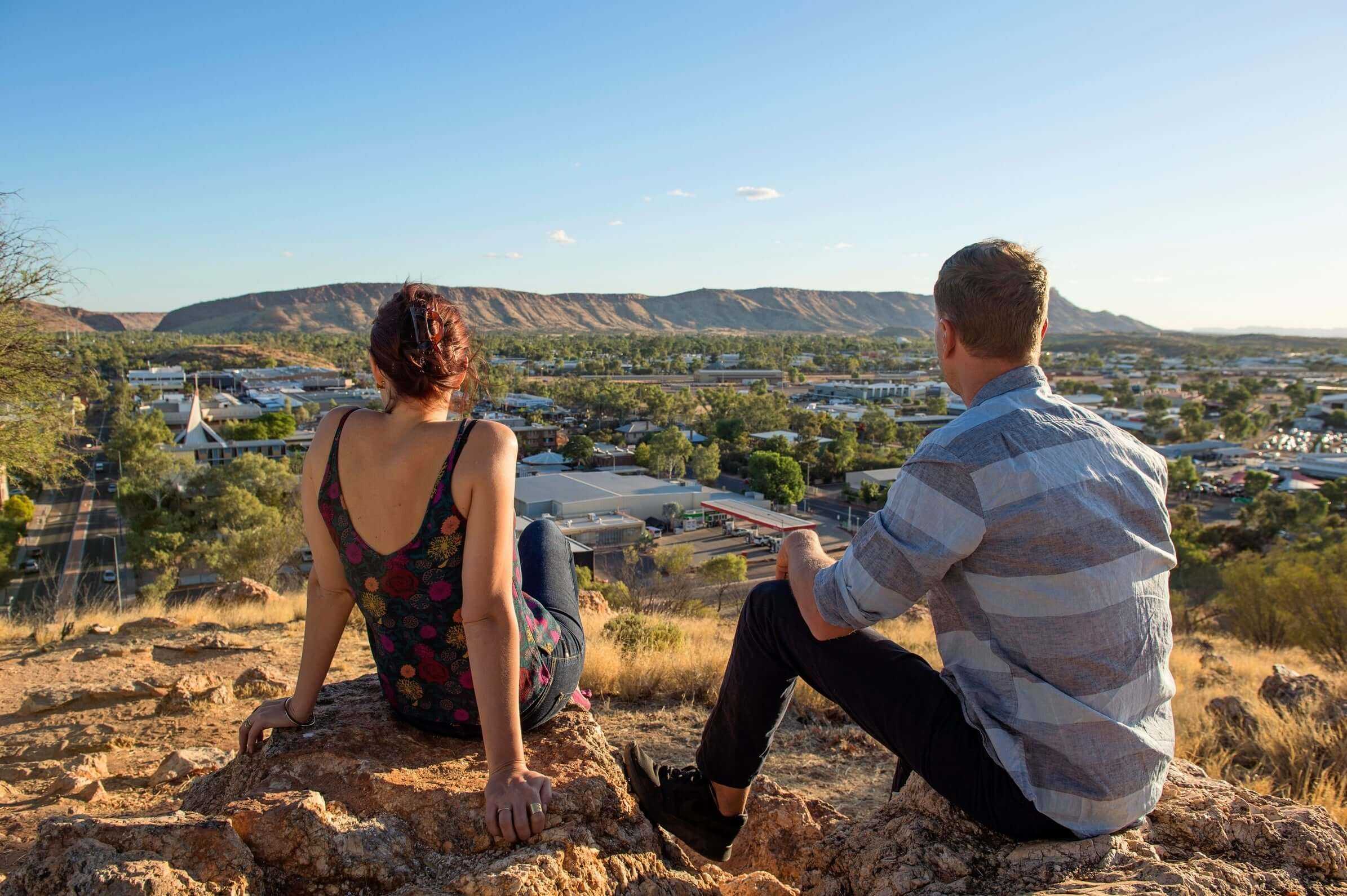 Couple overlooking Alice Springs township, starting point for Larapinta Trail 5-Day Expedition in West MacDonnell Ranges.