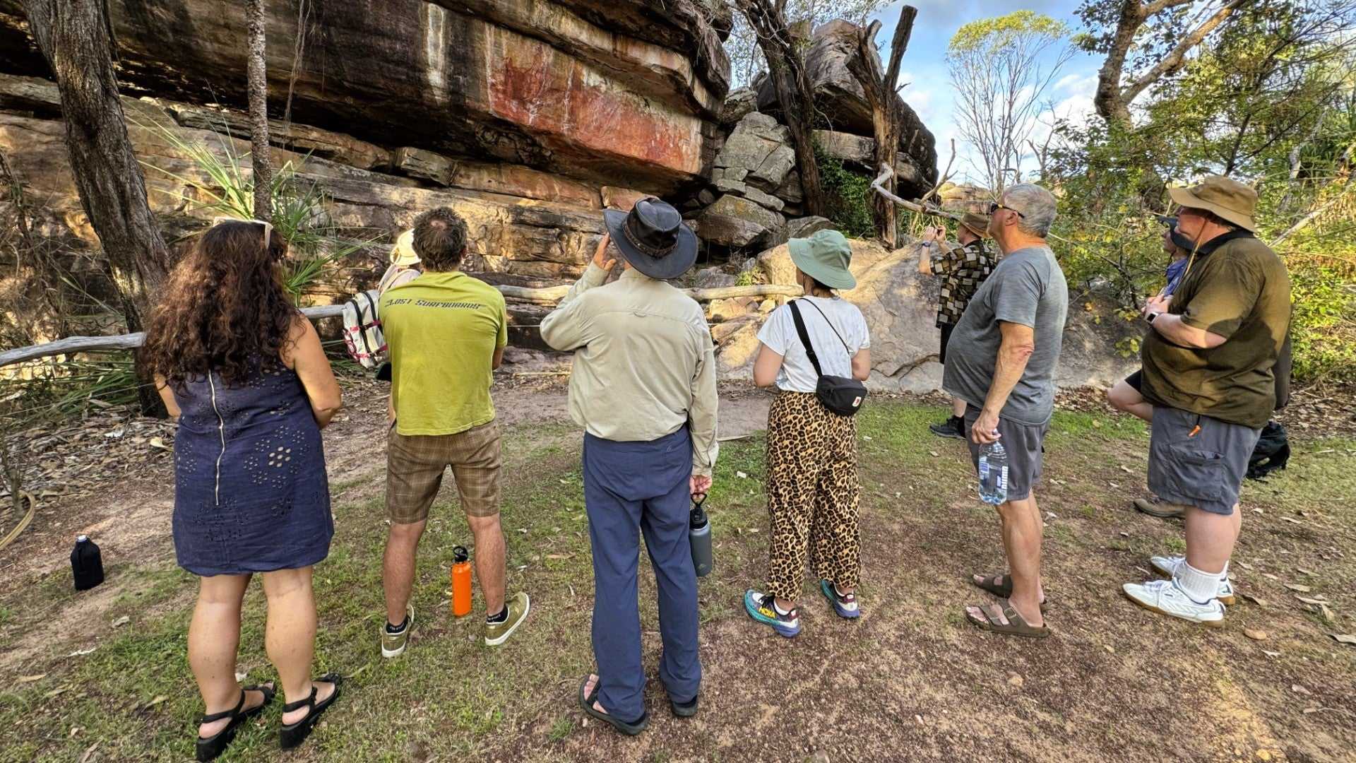 Visitors observe Aboriginal rock art on cliff wall on Kakadu Katherine Gorge Tour | 4-Day Comfort Travel. Cultural heritage site visit.