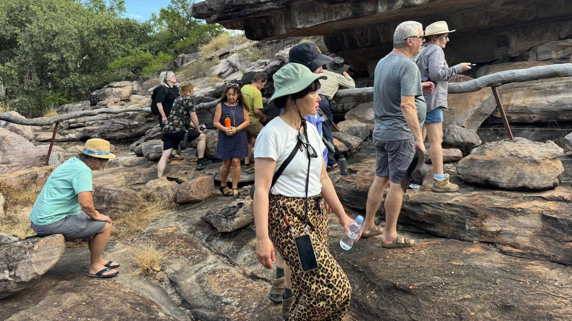 Visitors explore Aboriginal rock art site on Kakadu Katherine Gorge Tour | 4-Day Comfort Travel. Cultural discovery in rugged terrain.