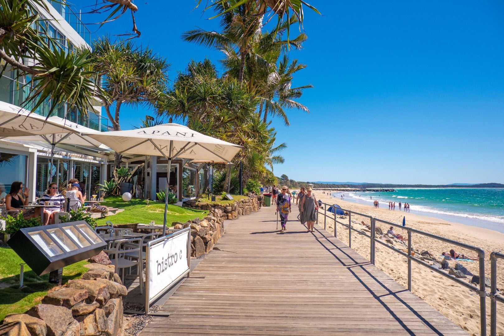 Beachfront boardwalk with cafes in Noosa, a relaxing stop on the Whitsundays Reef Tour from Brisbane to Cairns.