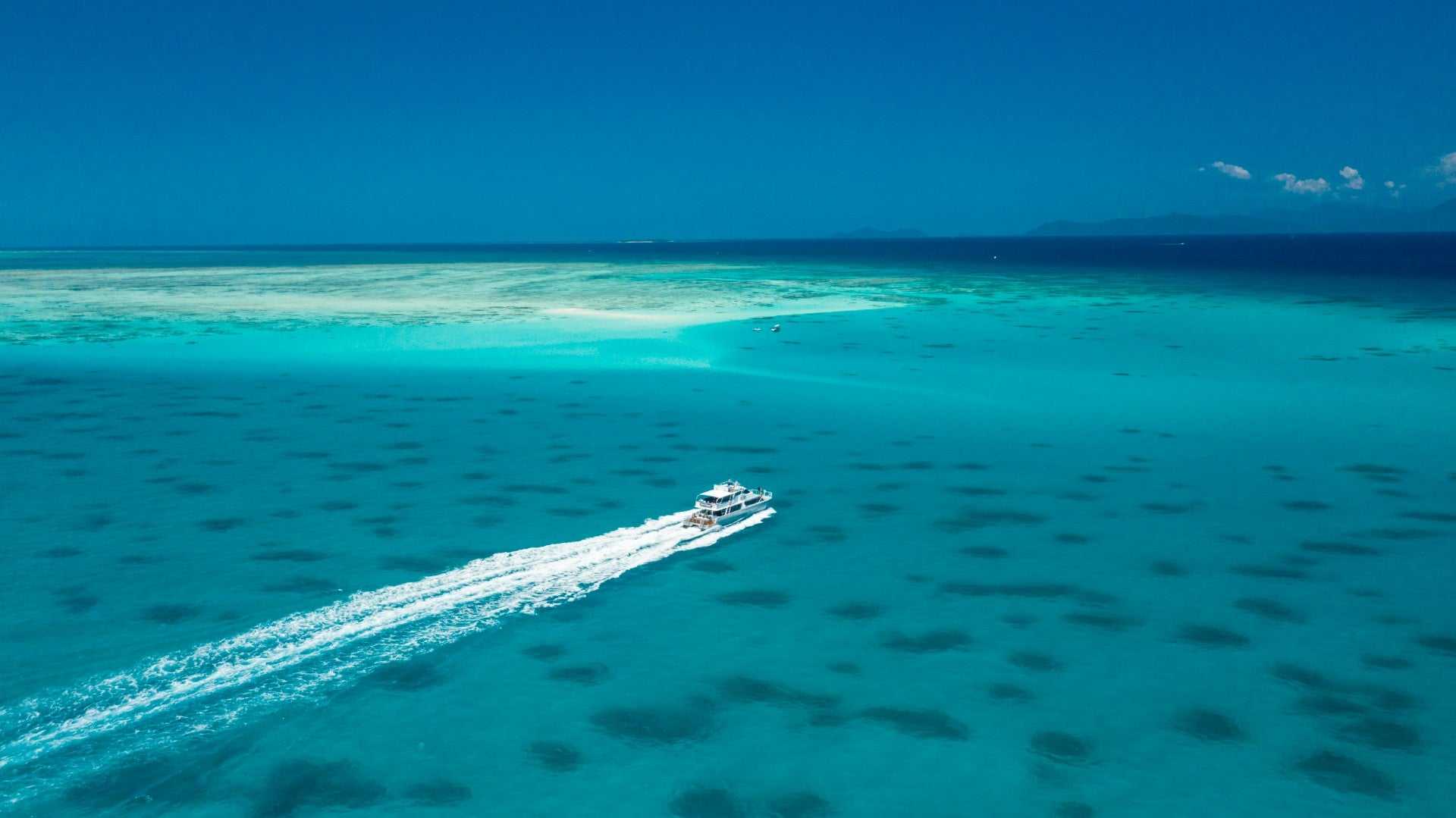 Speedboat cruises over turquoise reef waters, part of the Whitsundays Reef Tour from Brisbane to Cairns.