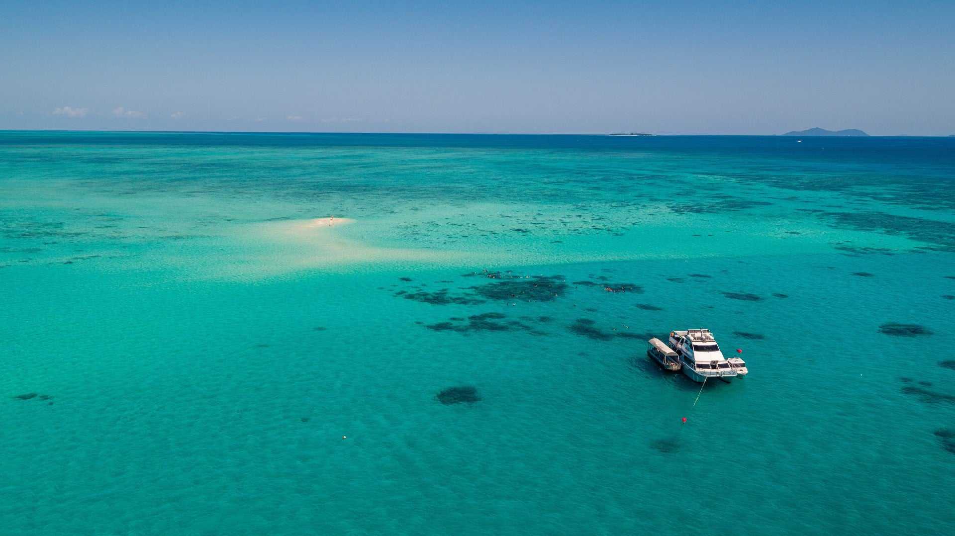 Boat anchored in turquoise waters of the Great Barrier Reef, ideal for snorkelling on the Whitsundays Reef Tour from Brisbane to Cairns.
