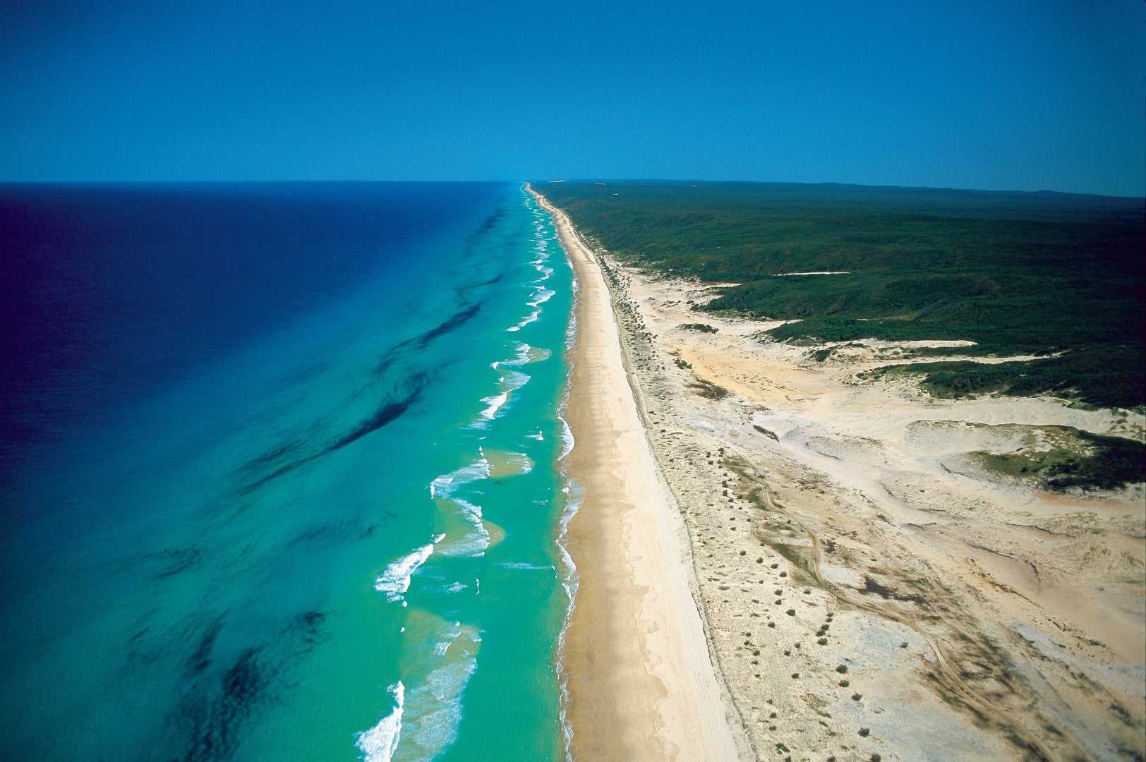 Fraser Island's 75 Mile Beach, iconic stop on East Coast Australia tour. Scenic drive on 8-day Sydney to Brisbane travel route.