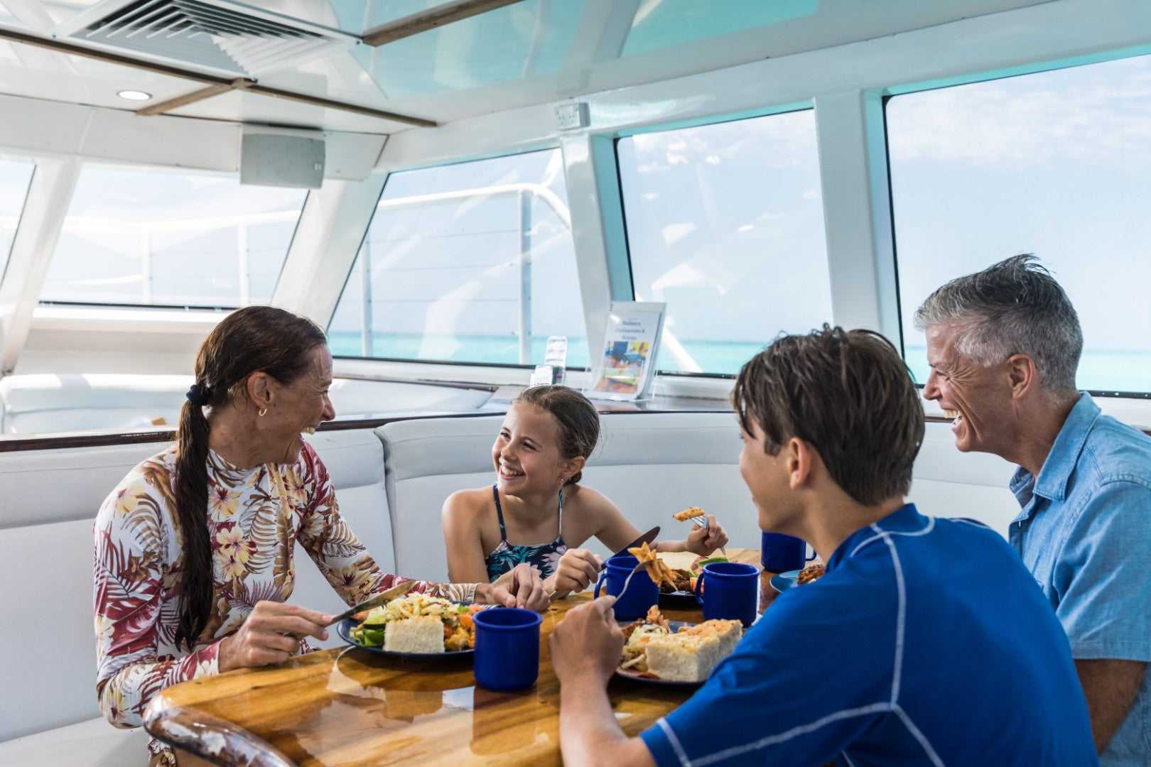 Family dining on reef cruise boat during East Coast Adventure 14/16-Day Small-Group Tour. All-inclusive marine day trip experience.