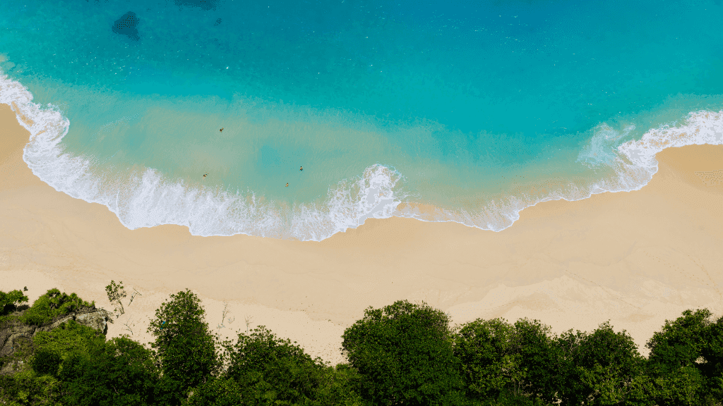 Aerial view of turquoise waves on a white sand beach, showcasing Gili Slow-Life in Bali Komodo Lombok Tours - Explore Culture & Nature.