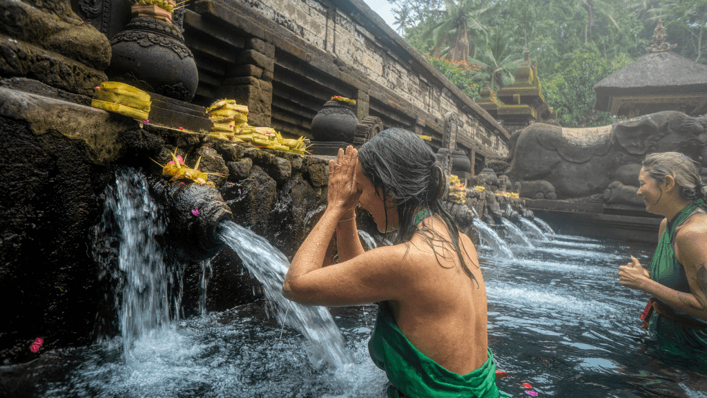 Women performing a water purification ritual at a Balinese temple, part of cultural immersion in Bali Komodo Lombok Tours - Explore Culture & Nature.