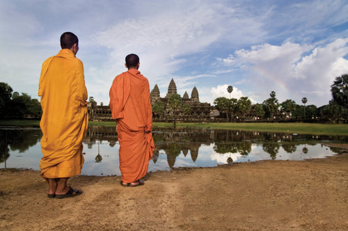 Two monks in orange robes admire Angkor Wat at sunrise, part of the Angkor to Islands 16-Day Tour - Khmer Culture to Thai Coasts experience.