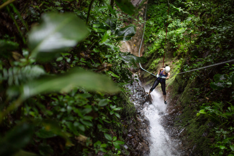 Adventurer rappelling down a jungle waterfall, showcasing outdoor thrills on the Central America Itinerary - Mexico to Panama | Travel Highlights.