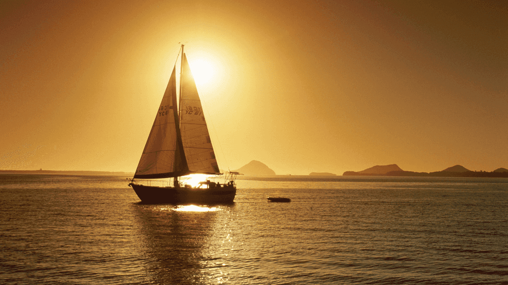 Sailboat at sunset in Whitsundays during East Coast Adventure 14/16-Day Small-Group Tour. Peaceful ocean sailing experience.