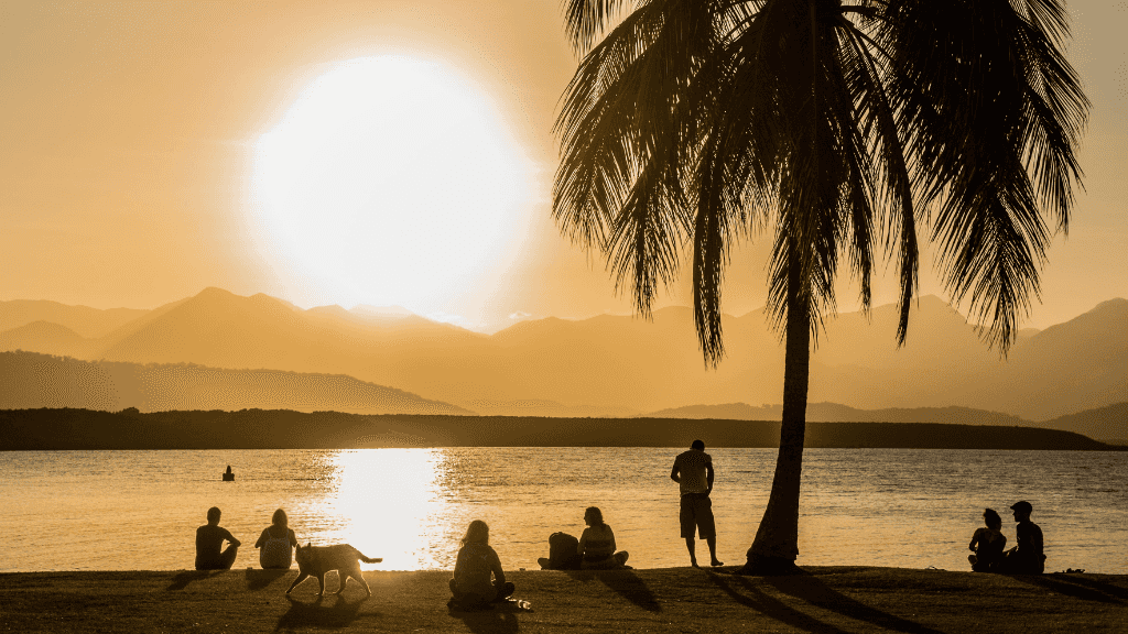 People watching sunset by the beach in Port Douglas on East Coast Adventure 14/16-Day Small-Group Tour. Relaxing tropical evening.