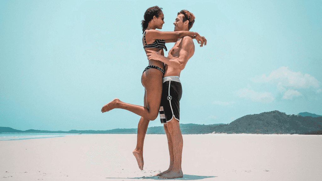 Couple embracing on Whitehaven Beach during East Coast Adventure 14/16-Day Small-Group Tour. Romantic beach moment in Whitsundays.