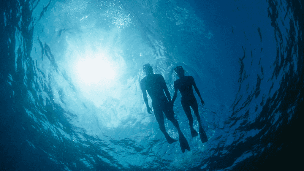 Couple snorkeling in Great Barrier Reef during East Coast Adventure 14/16-Day Small-Group Tour. Underwater adventure in crystal-clear waters.