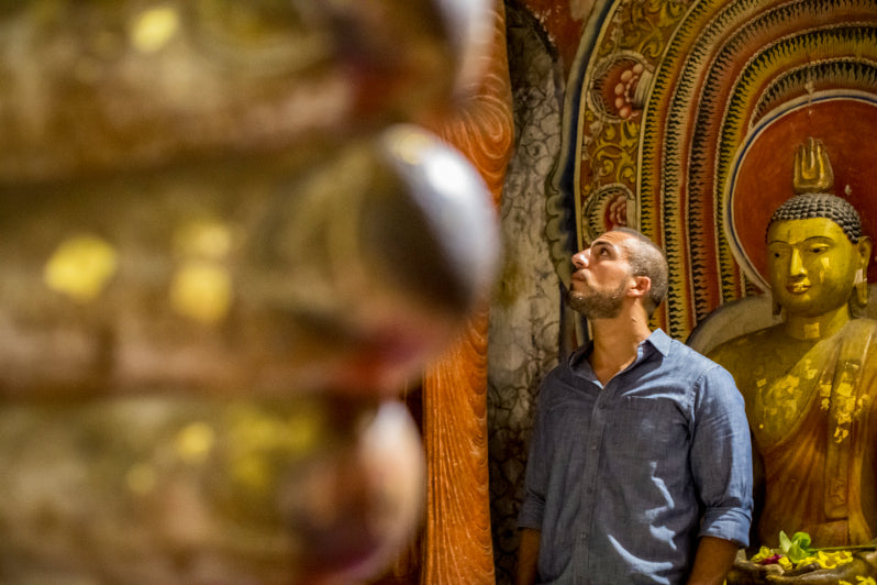 Man admiring ancient Buddha statue in Sri Lankan temple. Explore Sri Lanka - Land & Sea Tour Options includes cultural heritage experiences.