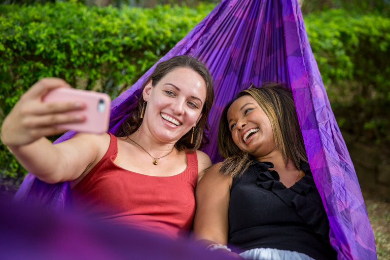 Two women relaxing in a hammock taking a selfie. Explore Sri Lanka - Land & Sea Tour Options includes leisure moments in tropical settings.