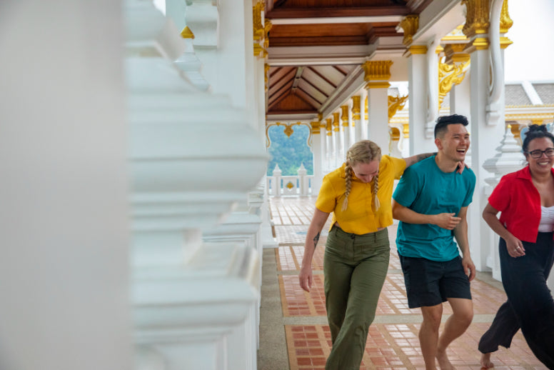 Friends laugh while exploring a Thai temple, part of the cultural highlights on the Angkor to Islands 16-Day Tour - Khmer Culture to Thai Coasts.