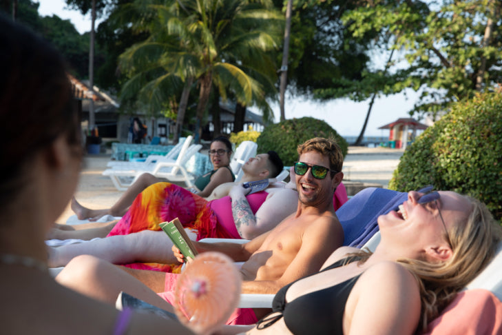 Travelers relax on beach loungers under palm trees, soaking up sun on the Angkor to Islands 16-Day Tour - Khmer Culture to Thai Coasts.