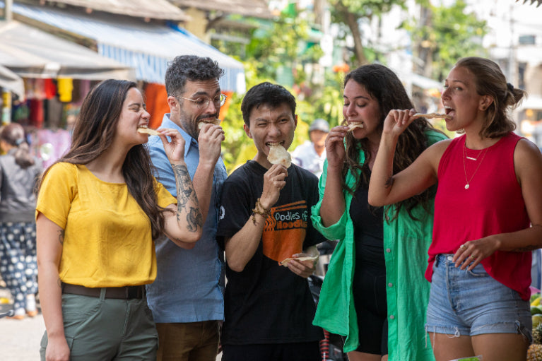 Travelers enjoying street food tasting with a local guide in Vietnam. Culinary adventure on Vietnam Hiking and Cycling Tour.