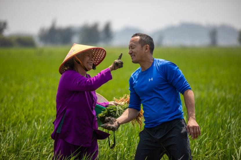 Local woman playfully interacting with tourist in a rice field. Authentic village experience on Vietnam Hiking and Cycling Tour.