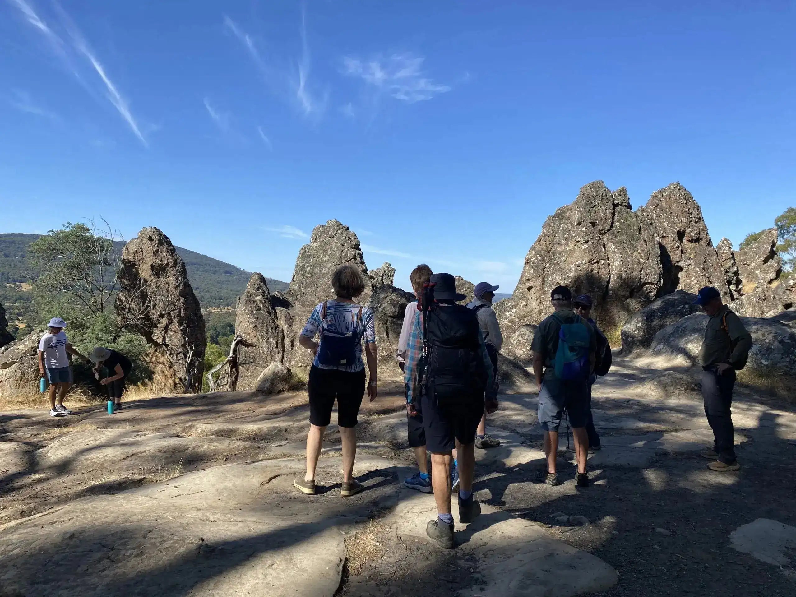 Group of hikers exploring rocky outcrops on the Goldfields Track Walking Tour. Perfect for moderate trekking and guided nature walks.