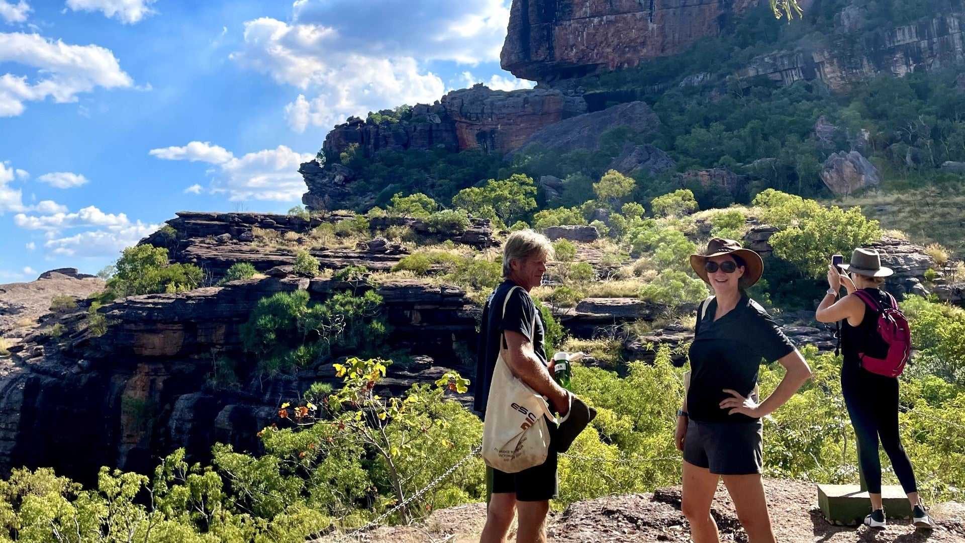 Hikers enjoying cliffside view at Kakadu Litchfield Camping Adventure - 3-Day Tour. Scenic lookout over forested escarpment.