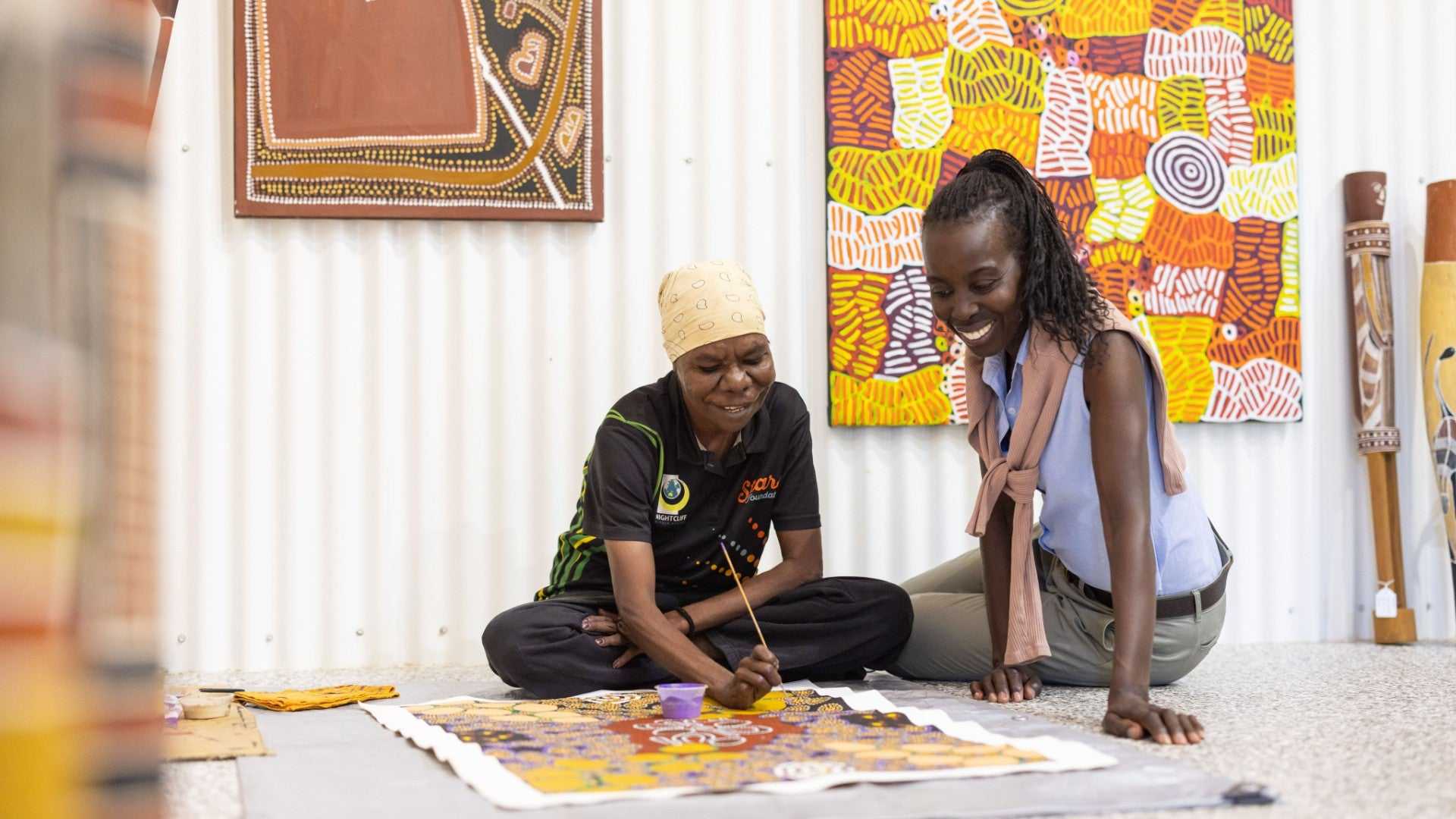 Local artist paints Aboriginal artwork with visitor on Kakadu Katherine Gorge Tour | 4-Day Comfort Travel. Indigenous art and storytelling.