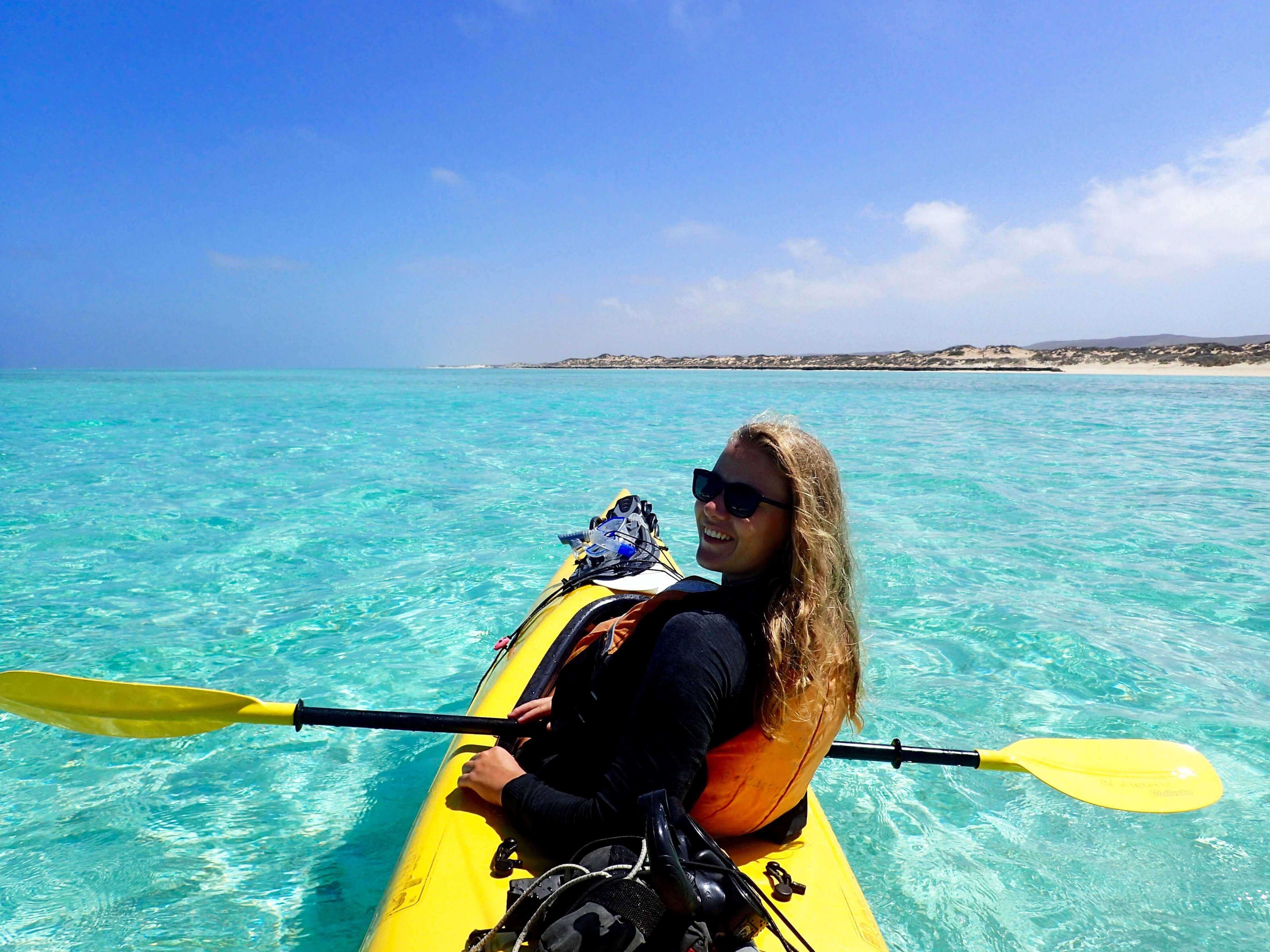 Woman kayaking in crystal-clear turquoise waters on the Ningaloo Safari 3-Day Kayak & Snorkel Tour. Ideal for coastal adventure seekers.