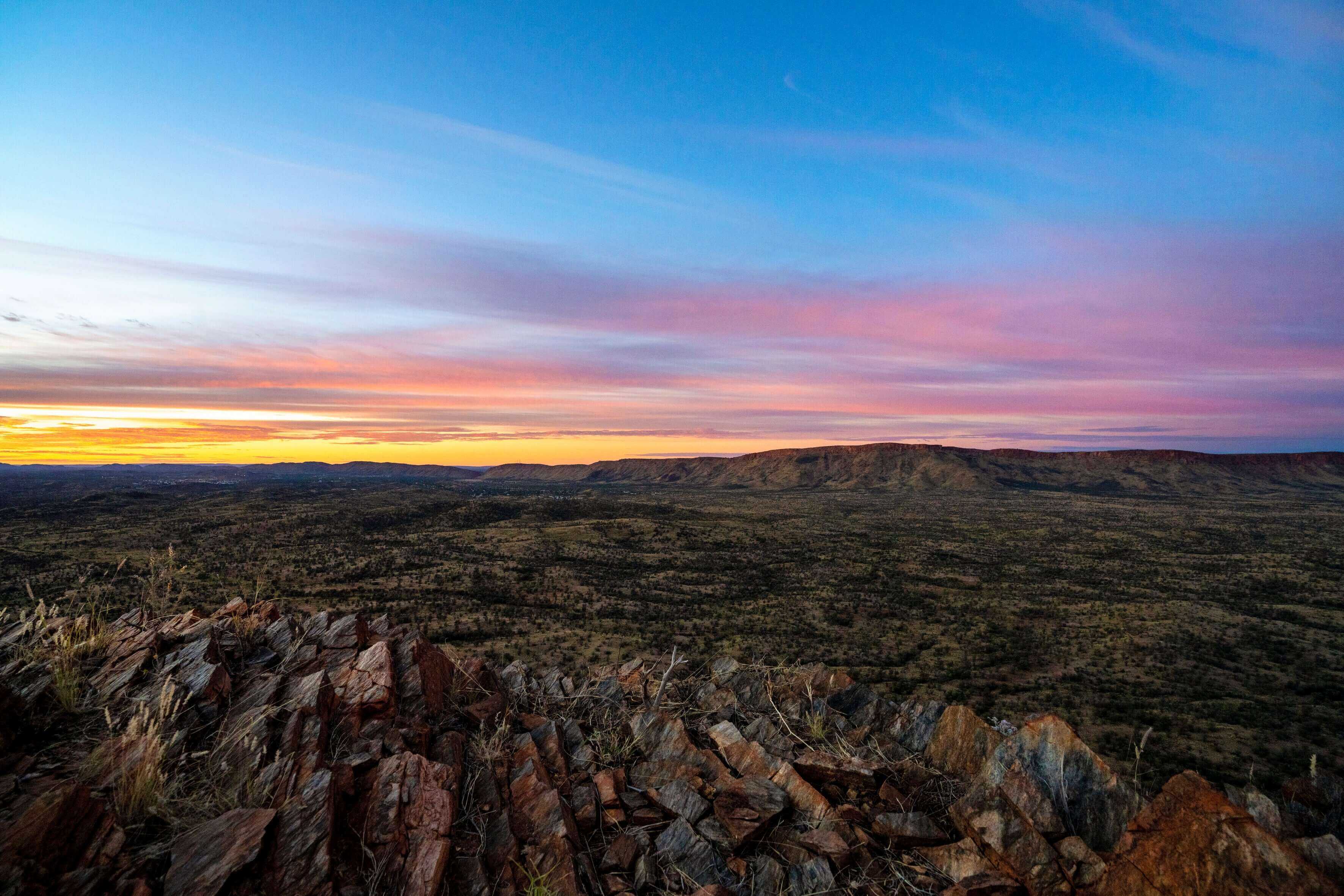 Colorful sunset over rocky desert terrain, capturing the magic of Larapinta Trail 5-Day Expedition in West MacDonnell Ranges.
