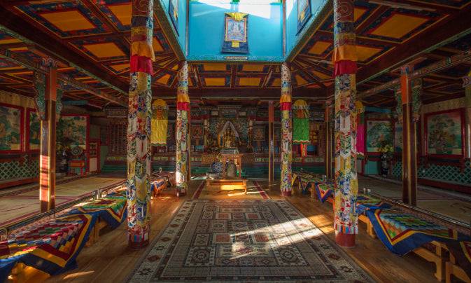 Colorful interior of a Mongolian Buddhist temple with ornate pillars and sacred altar, included in the Steppe to Sand - Mongolia Gobi Desert Tour.